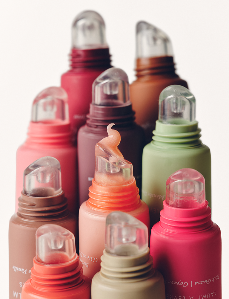 Collection of colorful lip balm bottles with clear caps on a white background